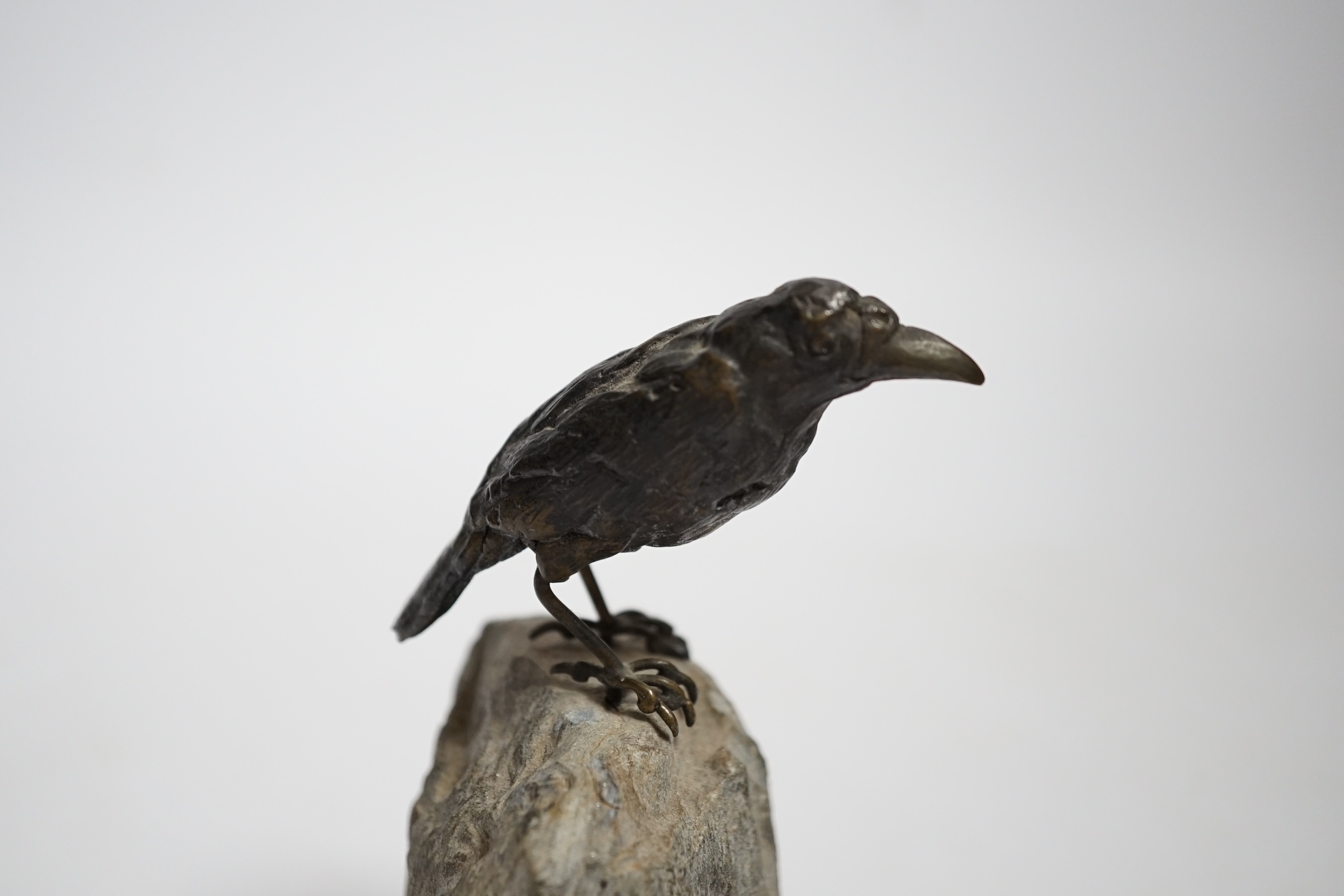 A cold painted bronze crow, raised on a stone base, 10cm high